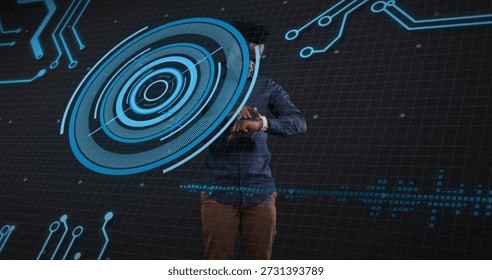 Showing tech presenter using blue hologram HUD in studio wearing blue shirt tan pants wristwatch. Interface, circuitry, holographic, grid, futuristic, neon, data
