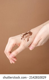 Showing Texture Scrub With Cocoa Coconut And Coffee On Hand On Brown Background. Spa And Home Care Concept, Beauty Procedures, Vertical Photo