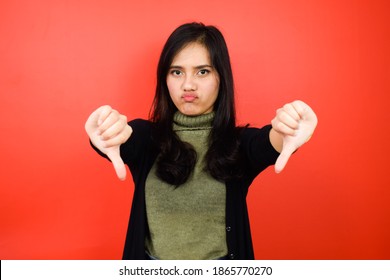 Showing Thumbs Down, Disagree Sign Of Young Beautiful Asian Women Using Black Sweater With Red Isolated Background