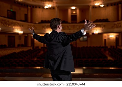 Showman. Middle Age Male Entertainer, Presenter Or Actor On Stage. Arms To Sides. View From Back Portrait Of Handsome Caucasian Male Public Speaker In Formal Elegant Suit Speaking To Audience