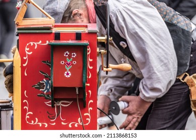 A Showman Playing A Street Organ Outdoors