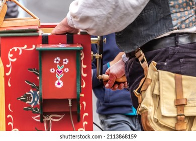 A Showman Playing A Street Organ Outdoors