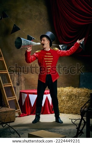 Showman. Vintage portrait of male retro circus entertainer expresses rejoice and announces start of show over dark retro circus backstage background. Concept of emotions, art, fashion, style