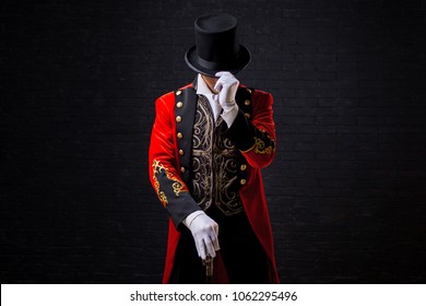 Showman. Young male entertainer, presenter or actor on stage. The guy in the red camisole and the cylinder. Looking down, hand on the hat - Shutterstock ID 1062295496
