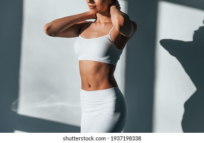 Shows her body. Young caucasian woman is indoors at daytime.