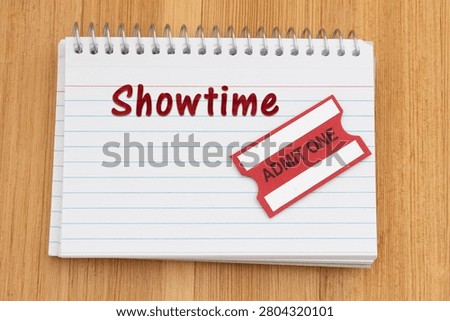Showtime text on a spiral notebook of index cards with admit one ticket on wood desk for entertainment and events