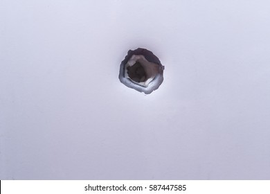 Shrapnel Hole On The Metal Fragment From The White Surface