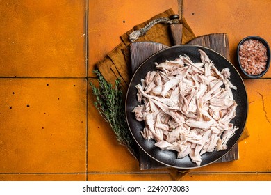 Shredded chicken meat in a plate. Orange background. Top view. Copy space.