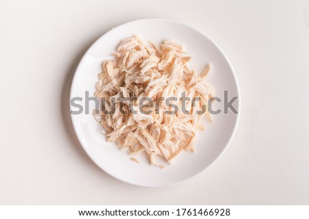 Shredded chicken on plate in white background.