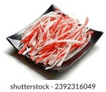 Shredded crab sticks in a black plate on white background. Close -up shot of the crab sticks.