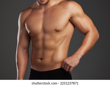 Shredded. Cropped shot of an unrecognizable and athletic young man posing shirtless in studio against a dark background. - Powered by Shutterstock