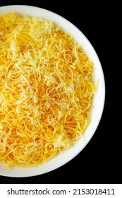 Shredded Mexican Cheese Mix In A White Bowl On A Black Background, Top View. Flat Lay, Overhead, From Above. 