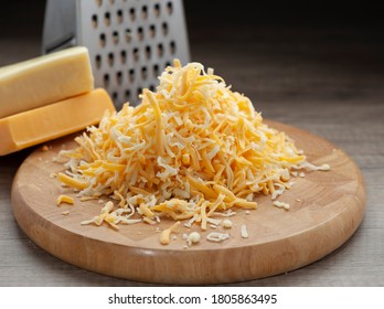 Shredded mozzarella and red cheddar cheese on wooden cutting board