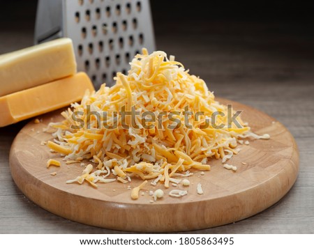 Shredded mozzarella and red cheddar cheese on wooden cutting board