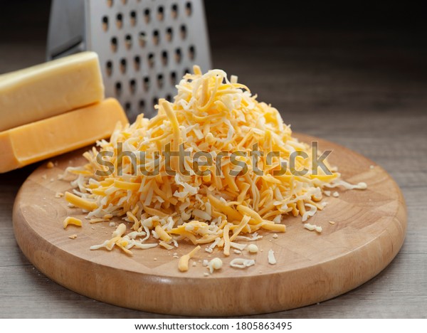 Shredded mozzarella and red cheddar cheese on\
wooden cutting board