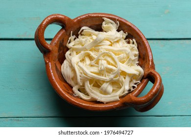 Shredded Oaxaca cheese also called quesillo on turquoise background. Traditional mexican food
