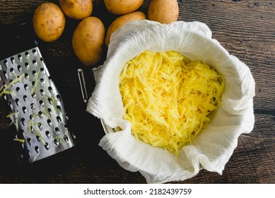 Shredded Yukon Gold Potatoes In A Cheese Cloth Lined Mixing Bowl: Overhead View Of Whole And Shredded Yellow Potatoes With A Box Grater