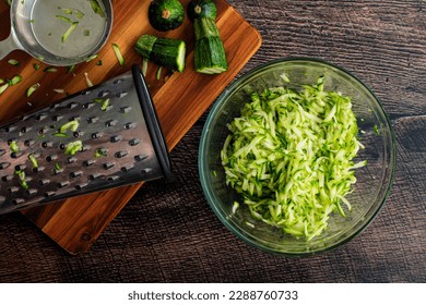 Shredded Zucchini in a Glass Mixing Bowl: Grated zucchini shown with a box grater and other tools