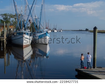 Shrimp boats at moorage, Darien, GA, Two boys fishing from a floating dock.