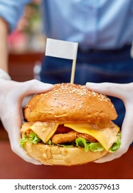 Shrimp Burger With Cheddar Cheese Served By Restaurant Waiter Wearing White Gloves For Cleanliness And Safety. 