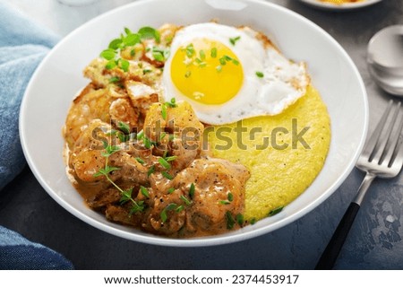Shrimp and cheesy grits topped with egg served for breakfast