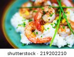 Shrimp and grits with cheese and chives on a rustic plate. 