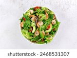 Shrimp salad with avocado, cherry tomatoes, green leaf mix salad and sesame seeds on a white background. Top view.