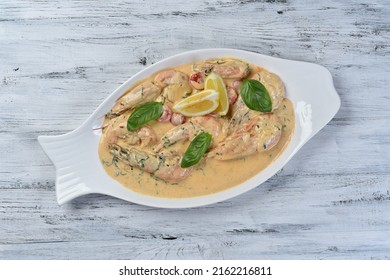 Shrimp in sauce in a white plate, a seafood dish on a gray table with lemon and basil
 - Shutterstock ID 2162216811