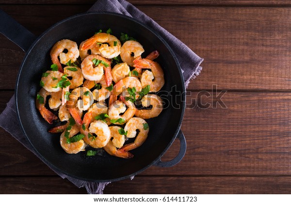 Shrimp Scampi traditional dish on\
wooden background top view. Shrimp fried in garlic batter with\
lemon and parsley. Healthy food. Clean eating. Space for\
text.