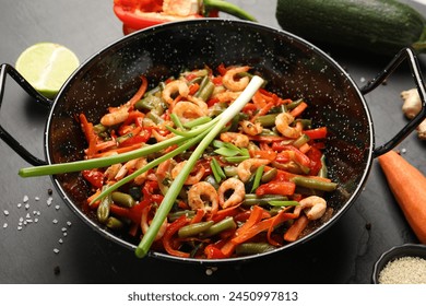 Shrimp stir fry with vegetables in wok and ingredients on black table - Powered by Shutterstock