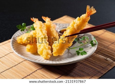 Shrimp tempura on a plate placed against a black background. Tempura is a Japanese food. It is Japanese fried shrimp.