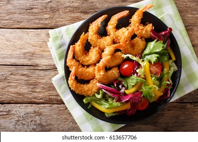 Shrimp tempura and salad of fresh vegetables close-up on a plate on a table. horizontal view from above