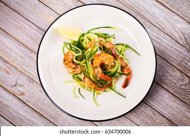 Shrimp with zucchini noodles. Prawns with vegetables and lemon. View from above, top studio shot