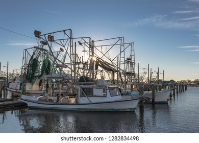 Shrimping boats at rest on empty docks as sun sets with clear skies