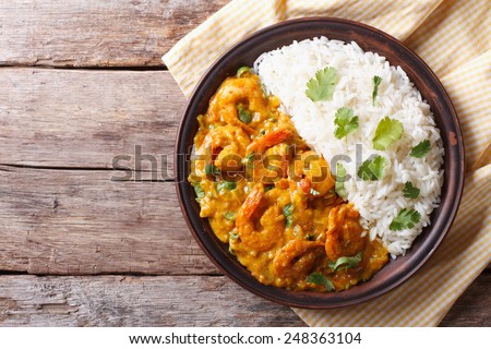 Shrimps in curry sauce and rice on a plate. horizontal view from above 