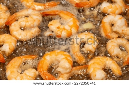 Shrimps are fried in oil in a frying pan.