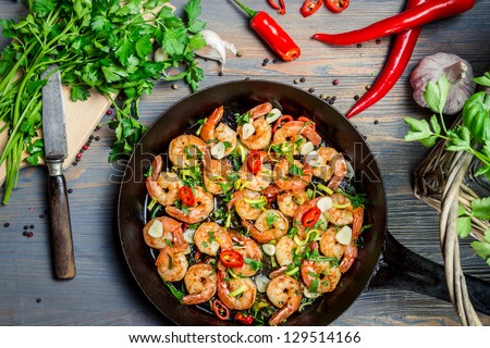 Shrimps fried on pan and fresh herbs