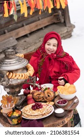 Shrovetide Concept Maslenitsa . Joyful Little Girl Bites A Large Bagel, Sits At A Table With A Samovar And Pancakes. Outdoor In Winter Time.