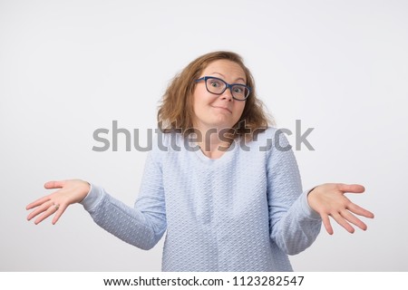 Shrugging norwegian woman wearing blue sweater in doubt doing shrug. Confused girl gesturing do not know sign on gray background