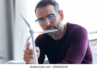 Shut Of Handsome Business Man  Working On New Alternative Energy Development Looking At A Model Of A Wind Turbine In Modern Startup.