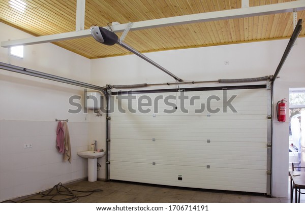 Shutter door or roller door and concrete floor\
outside .White Automatic shutters in a house . gates in the garage\
. Automatic Electric Roll-up Gate Or Push-up Door In The Modern\
Building Ground Floor