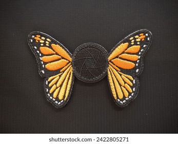 The shutterbug monarch morale patch emblem is velcro, used for attaching to clothing and bags.
