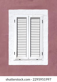Shuttered white window on the background of dark pink wall