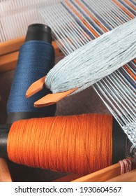 Shuttle with blue thread and two bobbins with indigo and orange yarns for weaving striped textile, upright format