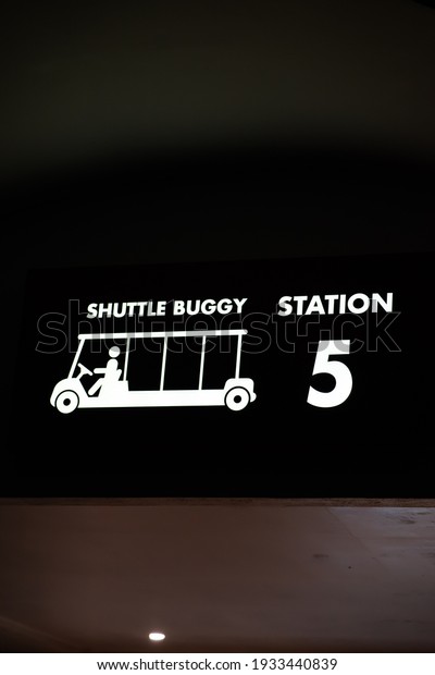 Shuttle buggy station signboard with lights\
attached to the\
ceiling.