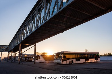 Shuttle buses at the parking lot of the airport near the jetway in the rays of the setting sun