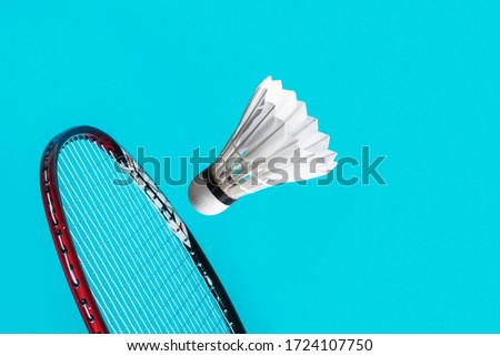 Shuttle cock badminton and racket in the blue background.