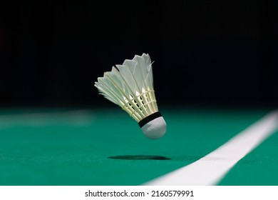 Shuttlecock floating on a green badminton court. Background, taken in low light.