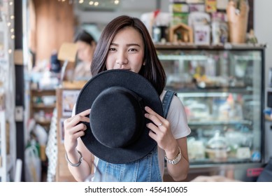 Shy Asian Girl And Black Hat In Coffee Cafe