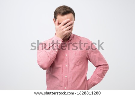 Shy embarrassed young man making faceplam gesture. Human reaction, feelings and attitude concept